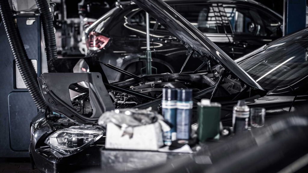 Auto mit offener Motorhaube in der Werkstatt in Nahaufnahme.